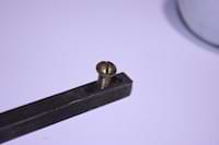photo of a brass screw threaded into a door handle spindle