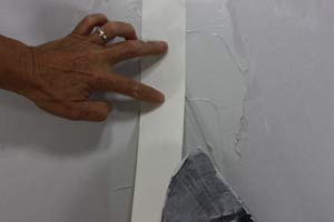 photo placing paper joint tape over a drywall seam