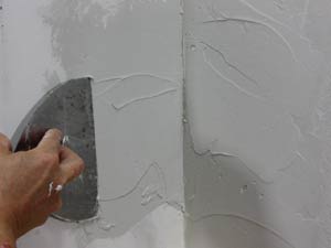 photo applying a second coat of mud on an inside drywall corner