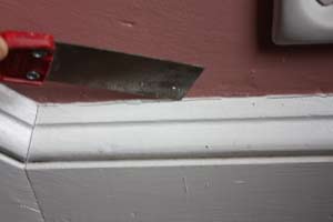 photo using a putty knife to clean out cracking caulk