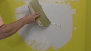 spreading a second coat of joint compound over a wall patch