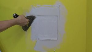 photo applying a patch to a drywall hole