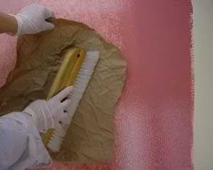 photo blotting wet painting glaze with craft paper to perfect a faux finish on a wall