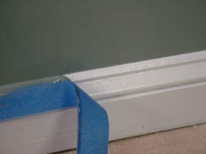 photo removing masking tape from a baseboard after painting the wall