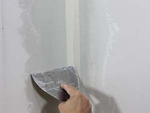 photo finishing a first coat of joint compound on an inside drywall corner
