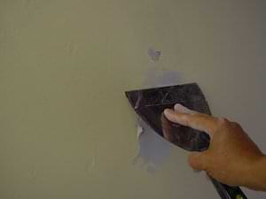 photo demonstrating how to push joint compound into a wall hole