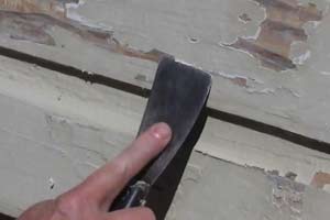 photo scraping peeling paint off house wood siding