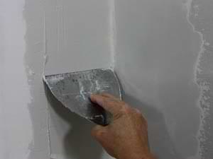 photo smoothing a second coat of joint compound on an inside drywall corner