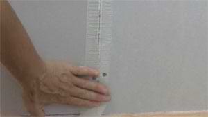 photo applying fiberglass mesh tape over a drywall butt joint