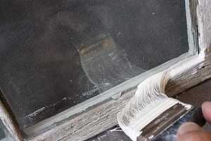 photo applying primer to bare wood on a window sash
